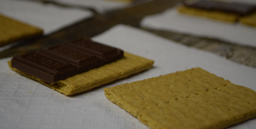 A chocolate bar placed on a rectangular biscuit on a white napkin.