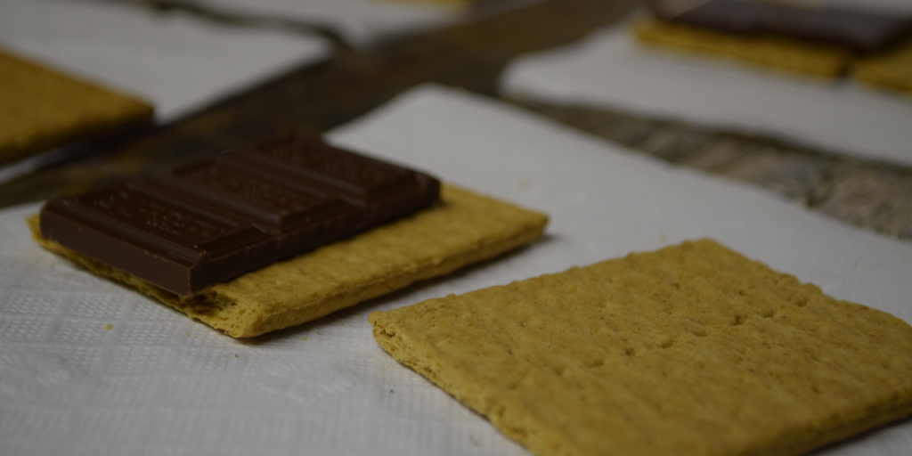 A chocolate bar placed on a rectangular biscuit on a white napkin.